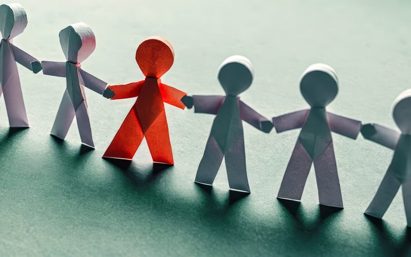 Diverse paper people chain on blue surface, inclusion, unity, teamwork. symbolize equal rights, community support, harmonious multicultural society. Concept solidarity, partnership, togetherness